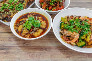 Assorted traditional dishes such as Fragrant Hotpot, Spicy boiled fish, mini lobsters, Chongqing grilled fish. Flat lay top down view of table of authentic Asia, China Sichuan Hunan food.