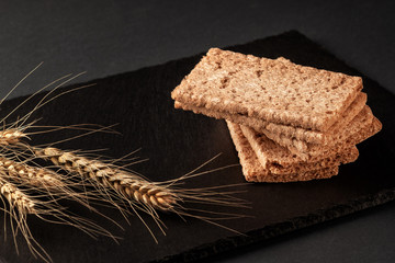 Crispy rye bread on a serving board with rye ears