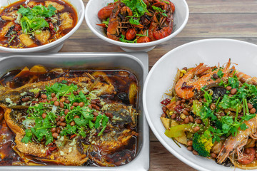 Assorted traditional dishes such as Fragrant Hotpot, Spicy boiled fish, mini lobsters, Chongqing grilled fish. Flat lay top down view of table of authentic Asia, China Sichuan Hunan food.