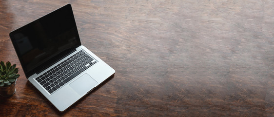 Laptop with black blank screen on a wooden desk - obrazy, fototapety, plakaty