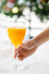 hands holding glass of orange juice
