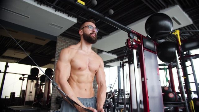 Male bodybuilder training chest muscles exercise using cable cross over machine for body mass. Ripped geek man in the gym
