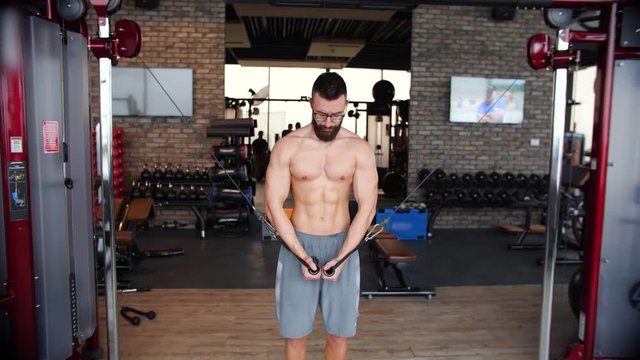 Male bodybuilder training chest muscles exercise using cable cross over machine for body mass. Ripped geek man in the gym