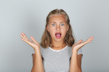 Portrait of young surprised girl on grey background