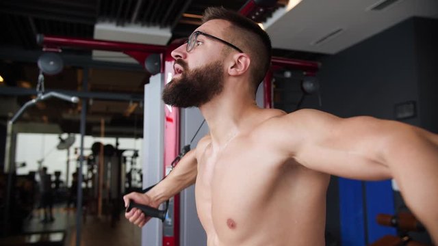 Male athlete training chest muscles exercise using cable cross over machine for body mass. Ripped geek man in the gym
