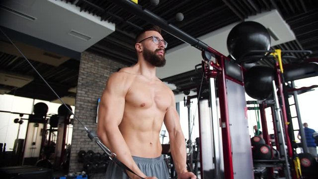 Geek bodybuilder at cable crossovers fitness men pumping up chest muscles. Workout fitness exercises and bodybuilding concept background