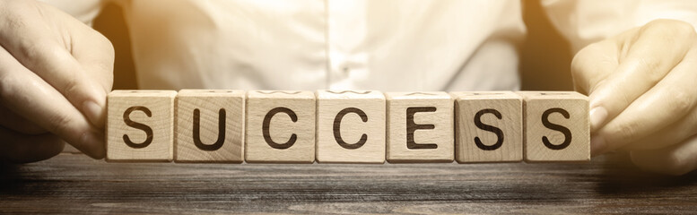 Wooden blocks with the word Success and businessman. Successful business concept. Achieving the goal, overcoming difficulties. The growth of profits and earnings in the company. Performance