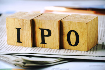 Text IPO on wood cube lay on news paper , stock investment concept.