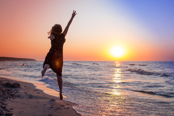 Attractive Girl Jumping on the Beach Having Fun, Summer vacation holiday Lifestyle. Happy women jumping freedom on white sand.Happy Carefree Woman in the blue dress Enjoying Beautiful Sunset.