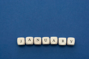 January lettering. Wooden blocks with january word over clasic blue blackground. Copy space.