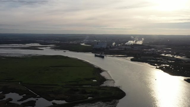 Wide aerial orbit view of Kemsley Industry in Kent, UK over the Swale Estuary