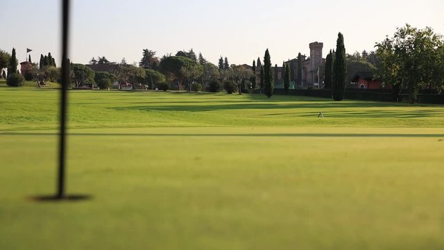 View Of A Green Golf Course, Castle, Hole And Flag On A Bright Sunny Day