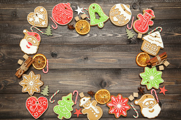 Christmas gingerbread cookies with candies, cinnamon and sugar cubes on brown wooden table