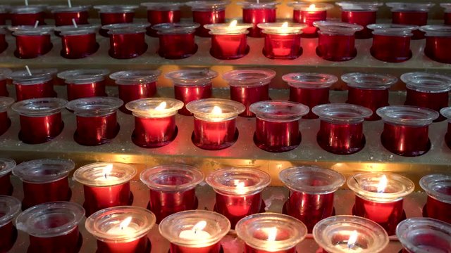 Huge amount of red candles arranged in the machines inside a cathedral, wishes and prayers to the saints represented