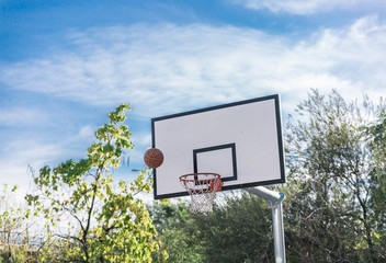 Basketball board of an urban basketball court and view of a ball in the air