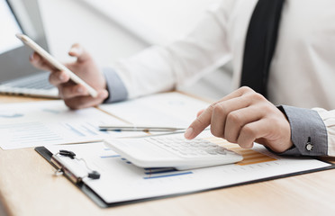 Business men use calculators to calculate the company's tax and revenue in the office, Financial and accounting banking concepts.