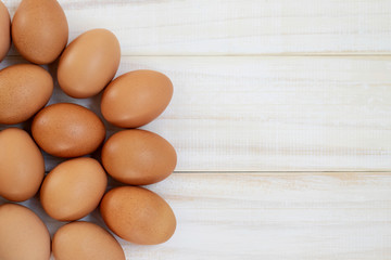 fresh chicken eggs from above on a white wooden background. Text space pattern.