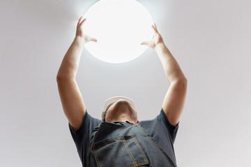 Electrician with white helmet checking lighting to the ceiling in the home, technician concept.