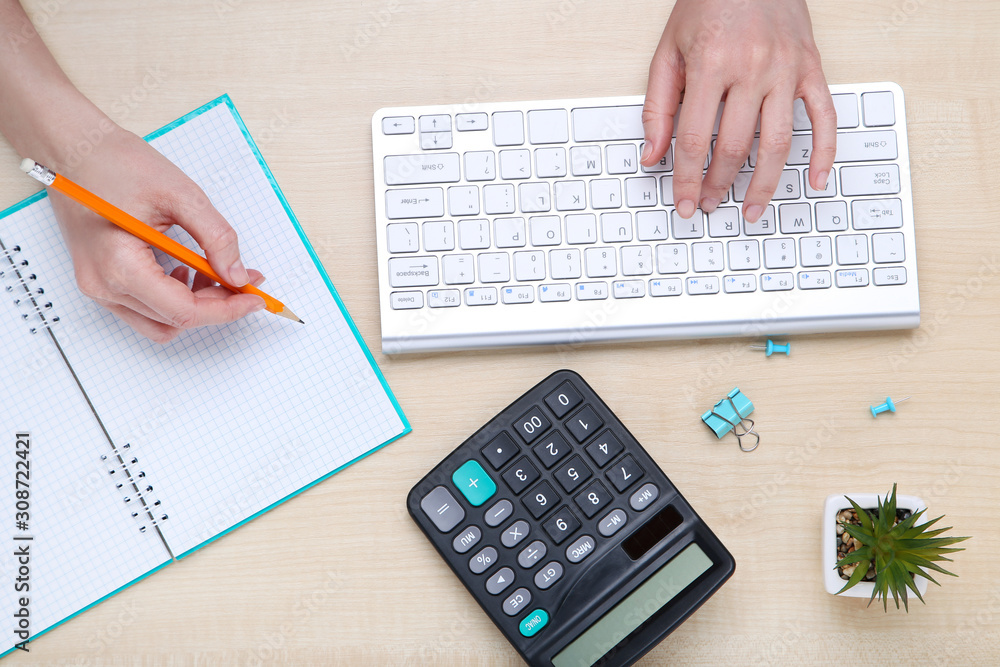 Fototapete Female hands typing on computer keyboard with notepad and calculator