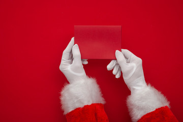 Father Christmas holding a red blank card. Overhead view