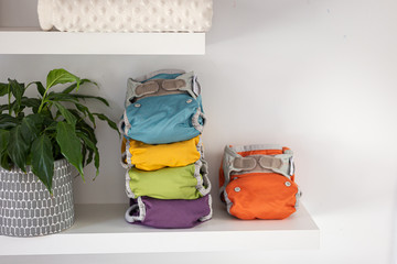 orange cloth diaper and diapers stacked on a white shelf, horizontal