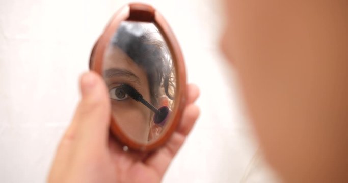 Young woman applying mascara make up