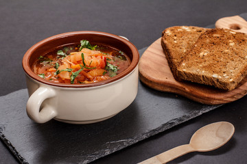 Ukrainian traditional borsch with rye bread on black background.