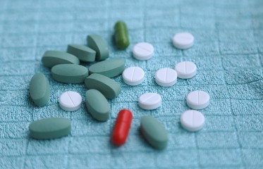 Capsules, white tablets, blue tablets in health pharmacy on blue background side view