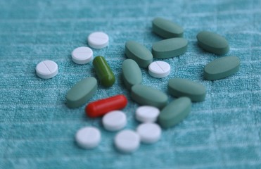 Capsules, white tablets, blue tablets in health pharmacy on blue background side view