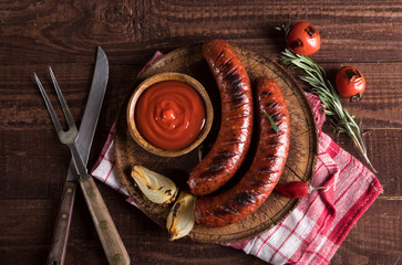 Grilled sausages on cutting board and wooden background