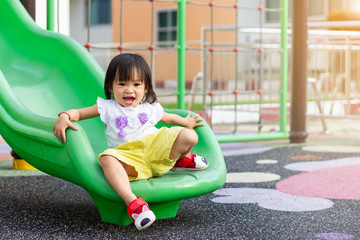Portrait image of 1-2 yeas old baby. Happy Asian child girl smiling and laughing. She playing with slider bar toy at the playground. Learning and active of kids concept.