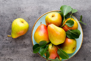 Fresh bio pear with leaves on the plate. Gray stone table.