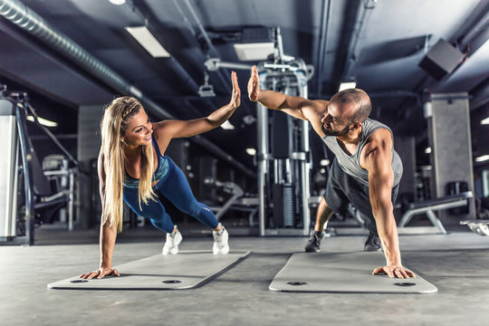 Sport couple doing plank exercise workout in fitness centrum. Man and woman practicing plank in the gym