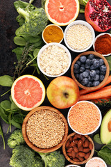 Healthy food clean eating selection: fruit, vegetable, seeds, superfood, cereals, leaf vegetable on rustic background