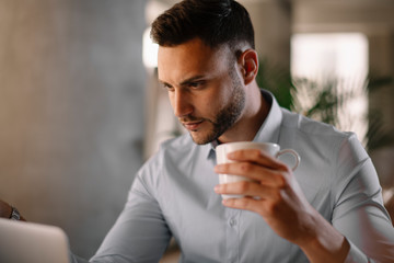 Portrait of handsome businessman working in office and drinking coffee.