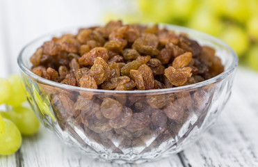 Portion of healthy Raisins on an old wooden table (selective focus; close-up shot)