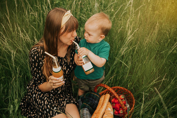 mother with baby in nature. beautiful woman in a summer dress. family on a picnic. mother and son drinks juice