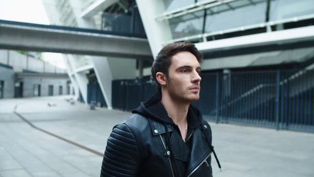 Closeup handsome man walking on emty city. Focused male model walking on street