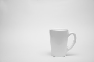 A white cup stands on a table on a white background.