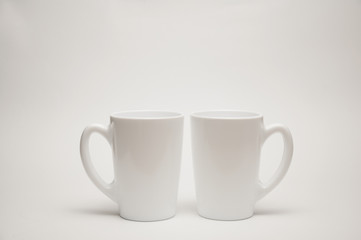 A white cup stands on a table on a white background.