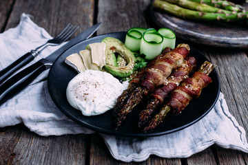 Baked asparagus in bacon with egg, avocado and cheese