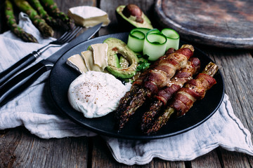 Baked asparagus in bacon with egg, avocado and cheese