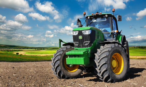  Modern, green tractor in the spring field work