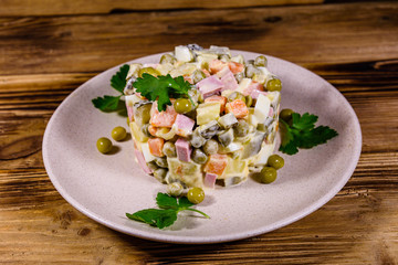 Ceramic plate with russian traditional new year salad olivier on a wooden table