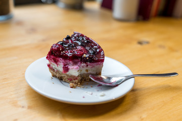 missing piece in a cheese cake with red fruits 