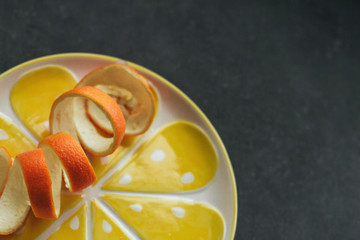  Orange peel on a yellow plate on a dark gray background.