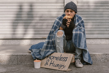 Poor man homeless with dirty hands eating piece of bread in modern capitalism society