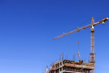 Construction site with worker and crane on blue sky background copy space. Constructing and building industry.