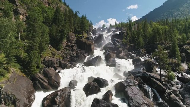 Rear drone flight near the foot of Uchar waterfall cascade above tourists.