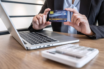 Businesswoman using laptop and holding credit card for paying detail page display online shopping purchase and entry security code to inputting card information